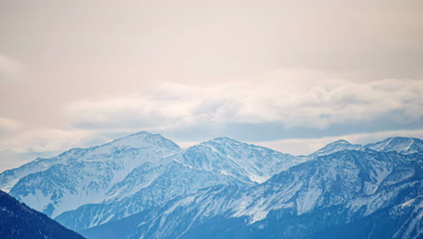 snow capped mountain range with clouds forming in a motion timelapse