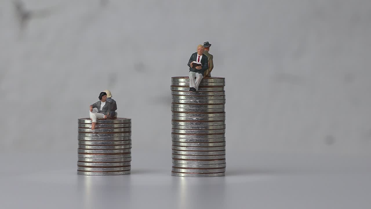 미니어처 남성과 미니어처 여성이 서로 다른 높이의 동전 위에 앉아 있습니다.