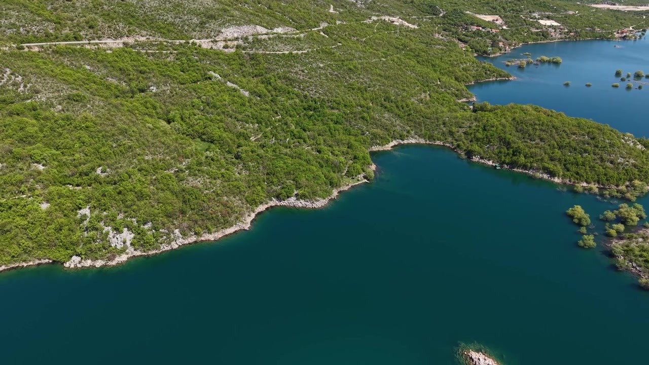 Ripresa con drone del Lago Slano vicino a Niksic, Montenegro, bacino d'acqua verde e costa in una giornata di sole.