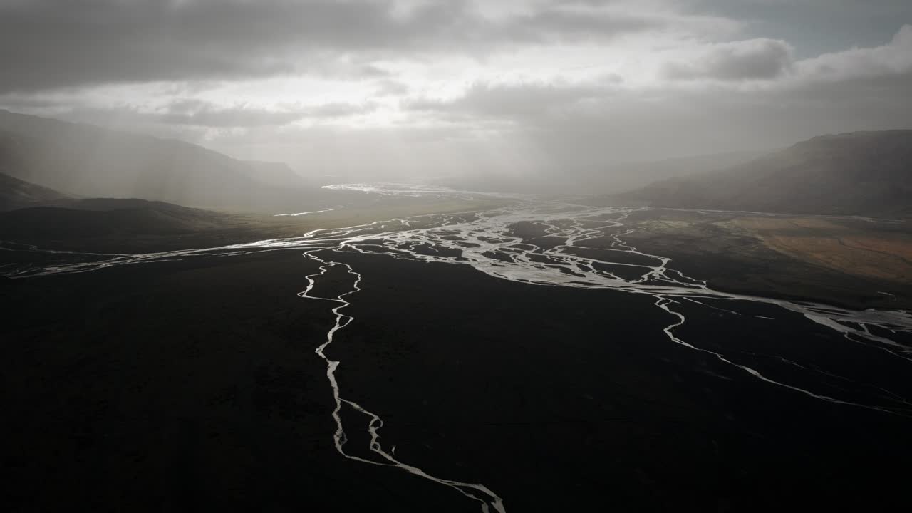 Aerial thor valley, flying over glacial river flowing through black volcanic floodplain, thorsm&ouml;rk dramatic epic landscape Iceland