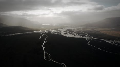 aerial thor valley, flying over glacial river flowing through black volcanic floodplain, thorsmörk dramatic epic landscape iceland