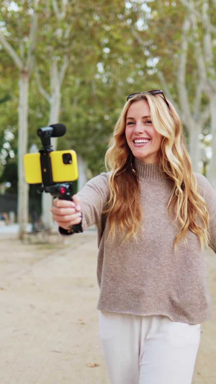 Giovane donna felice che registra un video con lo smartphone al parco