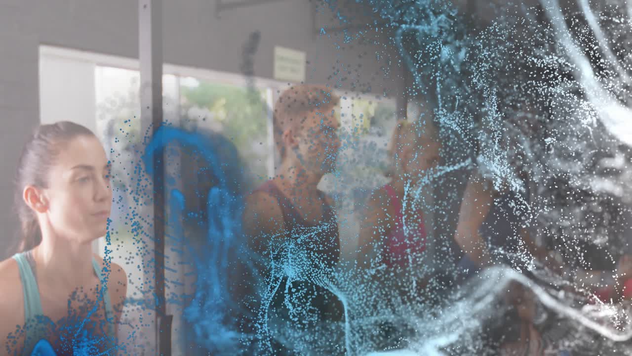 Particelle vorticose che si diradano stimolano un gruppo di benessere che pratica esercizi di respirazione alzando le braccia per effetti visivi.