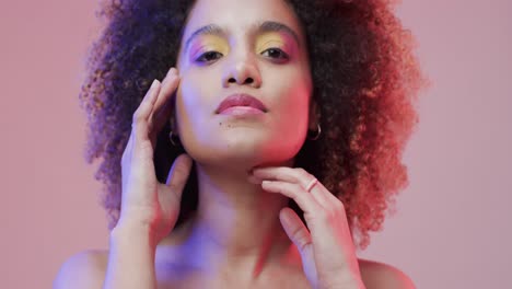 mujer biracial con cabello rizado oscuro en luz azul y rosa, cámara lenta