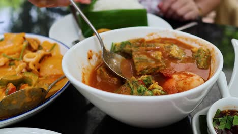 hands serving sour tamarind soup into plates