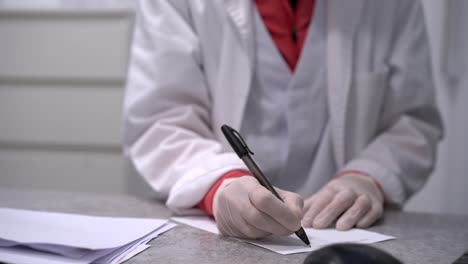 medic writing prescription on piece of paper in clinic