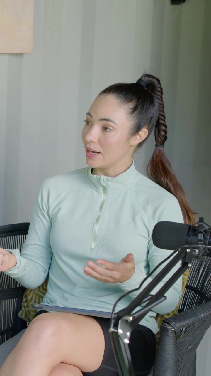 Vertical video: Reacting to cue, host in mint top black shorts holding tablet talking at studio mic