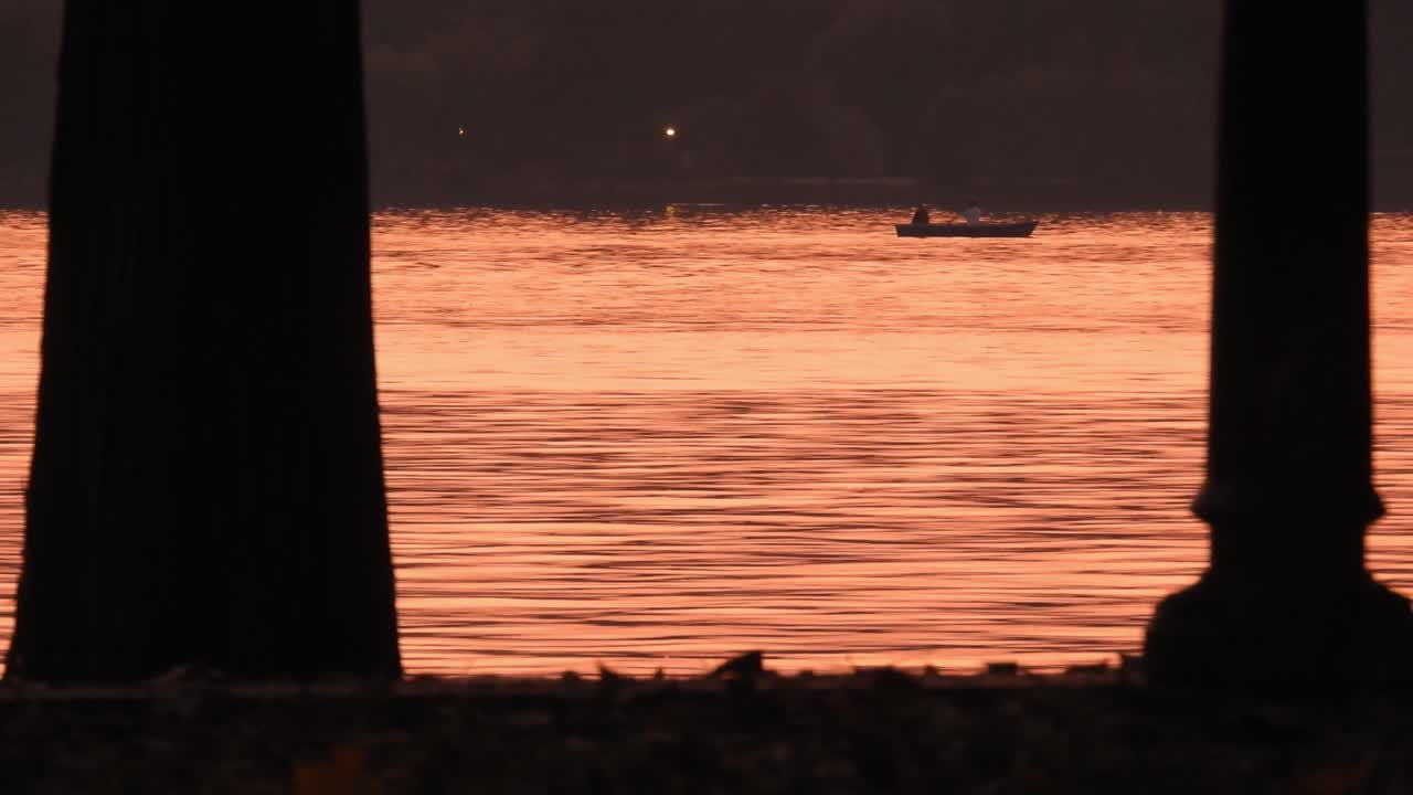 Peoples traveling on the ship under the sunset in yellow lights. People on boat in the lake at sunset