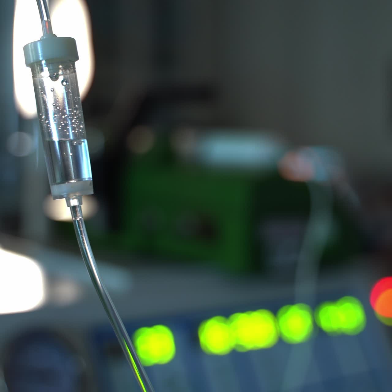 Medicine drops fall in the drop counter. Dropper close up. Operational surgery in blur at the backdrop