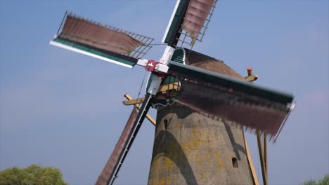 close-up of a windmill with turning blades against a blue sky