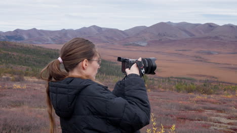 female tourist taking photos on the wilderness of yukon in canada - medium shot