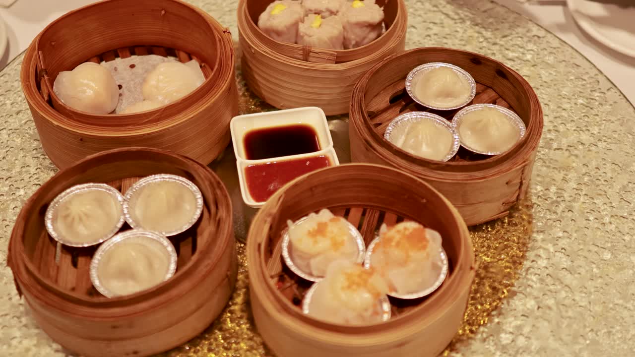 A variety of dim sum dishes on a spinning lazy Susan in a restaurant setting with warm lighting