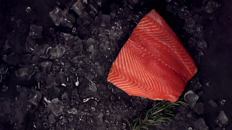 SUPER SLOW MOTION Overhead view of fresh uncooked salmon fillet falling onto ice pile. Shot with high speed camera, 420 FPS