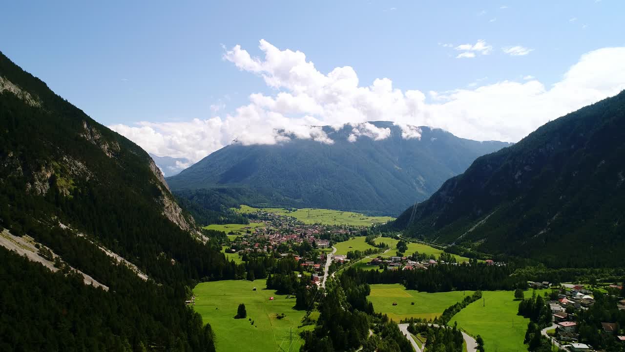 Vibrant green fields and distant peaks surround peaceful village, Austrian Alps