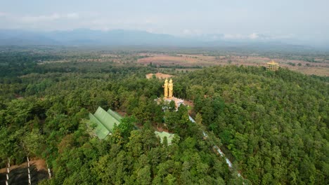 Aerial-drone-circling-Golden-Wat-Doi-Sapanyoo-with-a-large-staircase-leading-to-four-unique-buddha-statues-located-in-the-mountain-hills-of-Chiang-Mai-Thailand-surround-by-a-forest-on-a-sunny-day