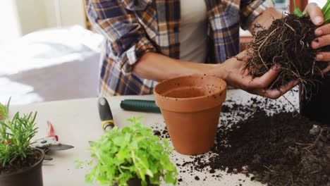 Sección-Media-De-Una-Mujer-Caucásica-Plantando-Macetas-En-Casa