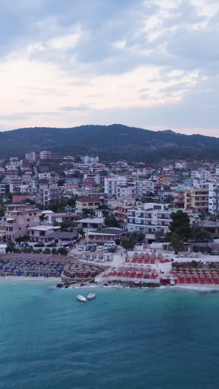Aerial view of the turquoise waters, beach and hotels on the coast of Ksamil, Albania. Vertical Video, Push Forward Shot