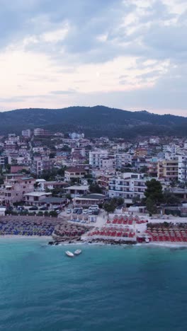 aerial view of the turquoise waters, beach and hotels on the coast of ksamil, albania. vertical video, push forward shot