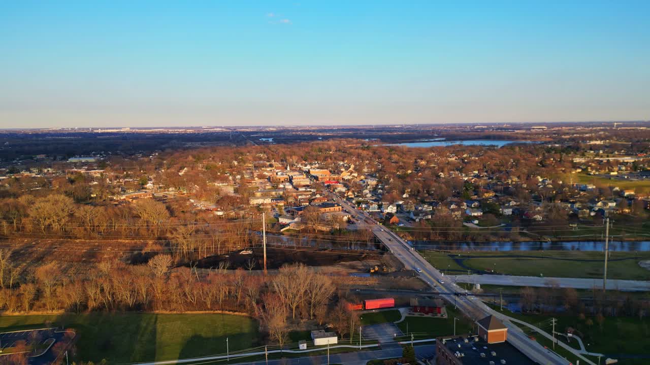 An aerial perspective captures the charming town of Plainfield, Illinois, bathed in the warm, golden light of a late afternoon sunset