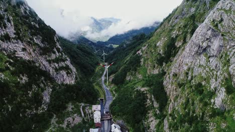 wind turbines rise in misty alpine gorge near plöckenpass italian-austria border