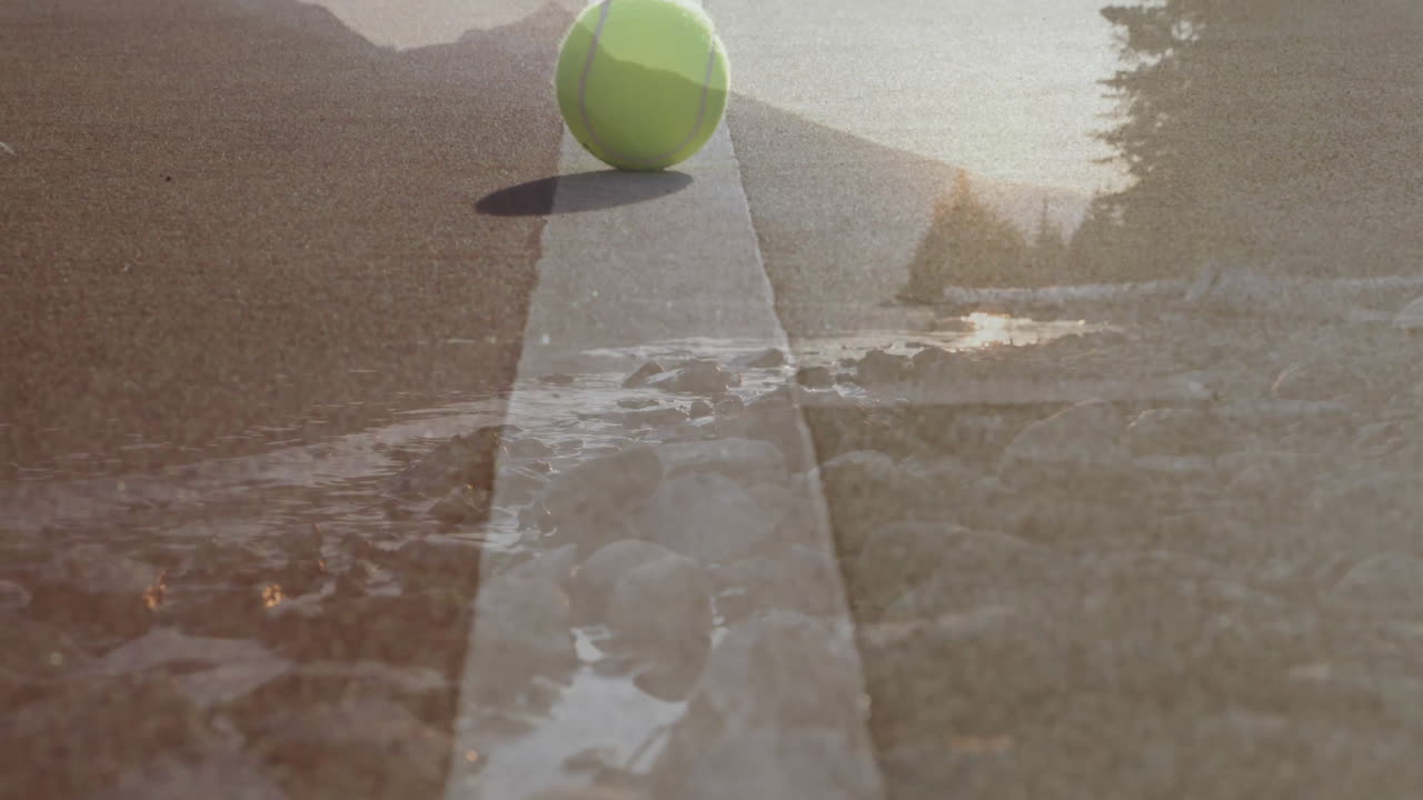 Tennis ball rolling along painted center line, creating double exposure of road and riverbank