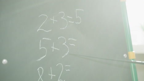 tutor shows unsolved maths task written on blackboard