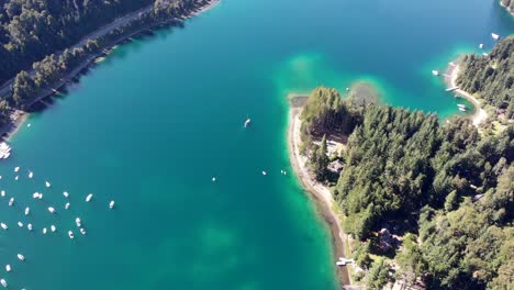 Descending-high-aerial-tracks-lone-sailboat-on-clear-blue-Nahuel-Huapi