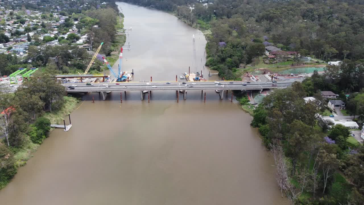 4K Aerial view of a brown river and a bridge under construction