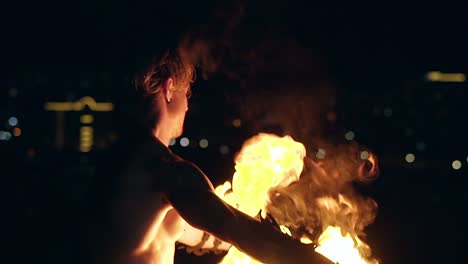 young blond male spins two burning pois slow motion shot close up