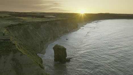 sunrise at fortrose cliffs with rock pinnacle on south island new zealand, aerial