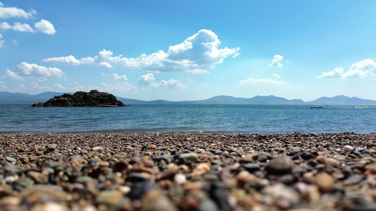 Majestic Snowdonia mountain range behind ocean rock formation emerging from shimmering seascape