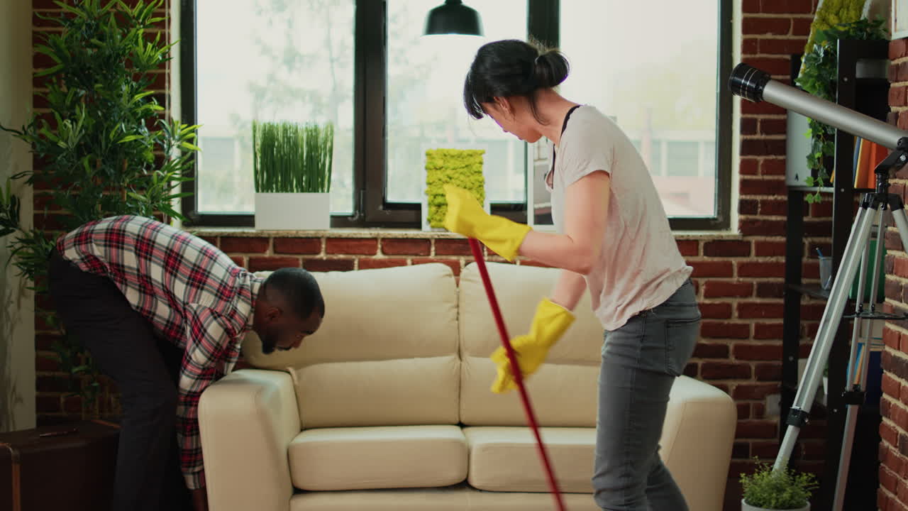 Young couple washing wooden floor with mop