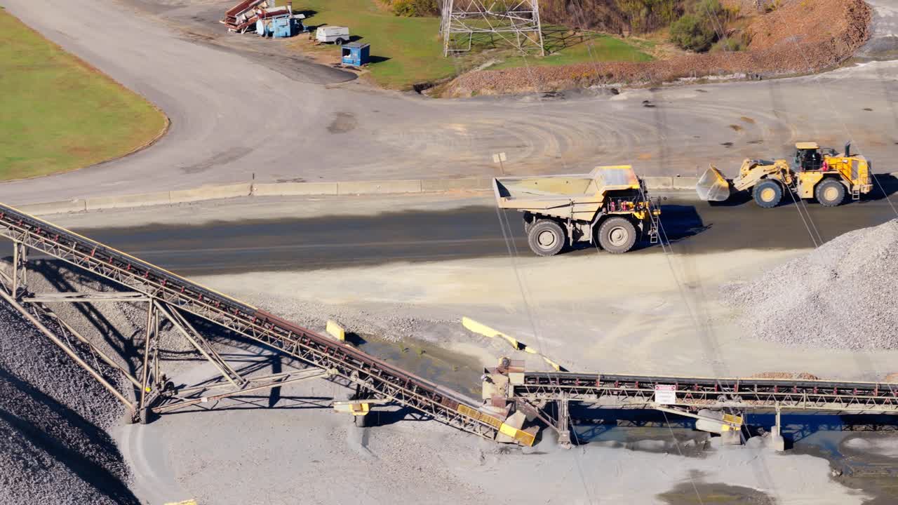 処理工場内のコンベアベルトを通過する採石場の重機（ダンプトラックとショベルカー）を空中から追跡