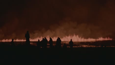 silhouettes of people observing the fiery eruption of grindavik volcano in sundhnúkur crater, iceland, at night