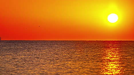 Vibrant-colorful-sunset-over-ocean-surface,-boat-sails-into-view,-fusion-time-lapse