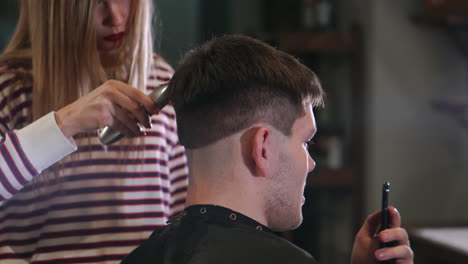 männlicher haarschnitt mit elektrischem rasierer. nahaufnahme von haarschneiderfrisur. professioneller friseur, der haare mit einem haarschneider schneidet. mann, der mit einem elektrischen rasierer frisuriert