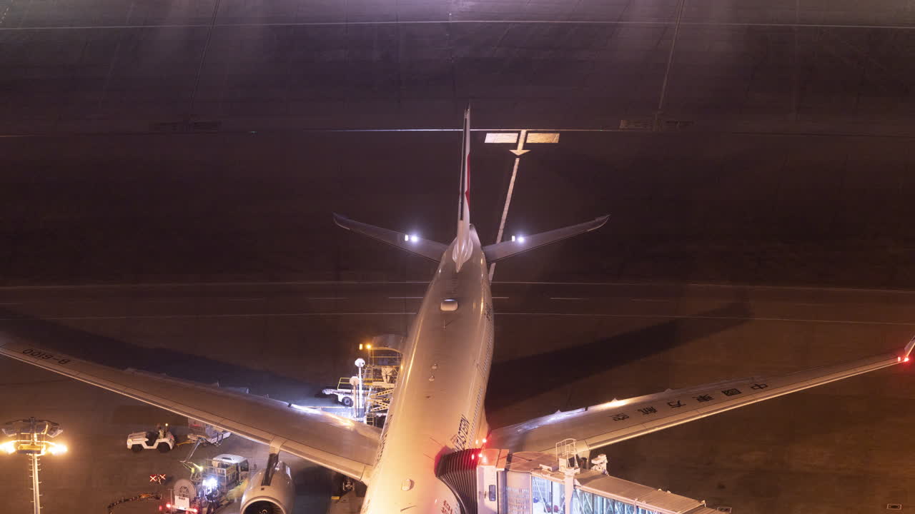 Time-lapse di un aereo al gate dell'aeroporto con attività del personale di terra di notte