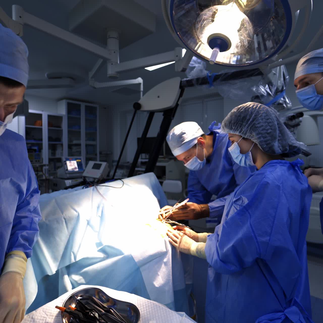 Professional team of doctors performing operation. Big diverse group of surgeons in modern well-equipped operational theatre