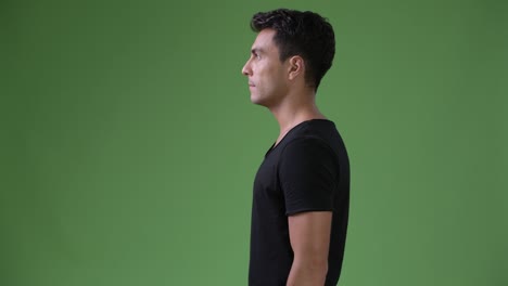 young handsome hispanic man against green background