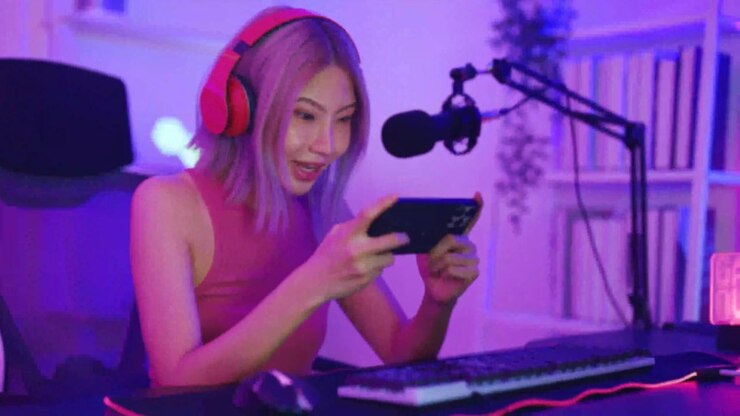 Giovane donna asiatica felice che gioca a un gioco mobile su smartphone