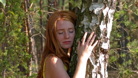 young redhead woman embracing tree in forest