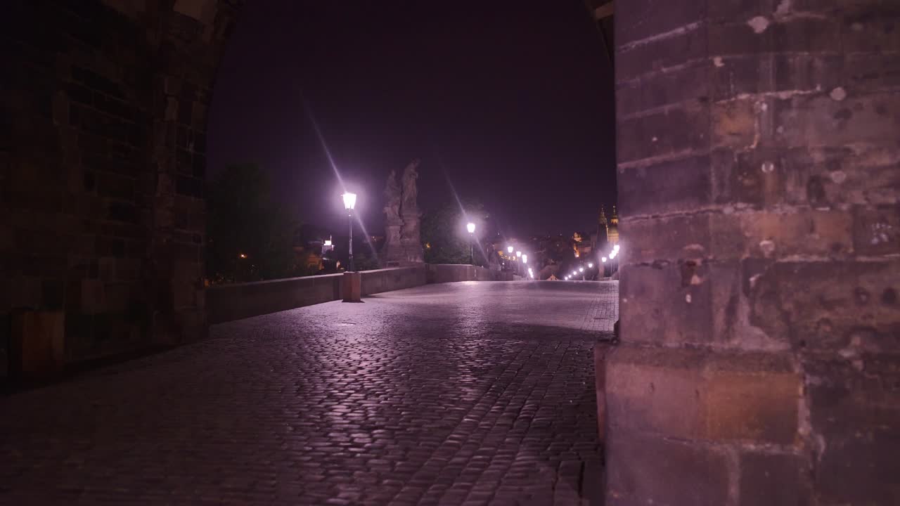 Arch Entrance To The Famous Charles Bridge Over Vltava River In Prague, Czech Republic In The Evening - dolly shot
