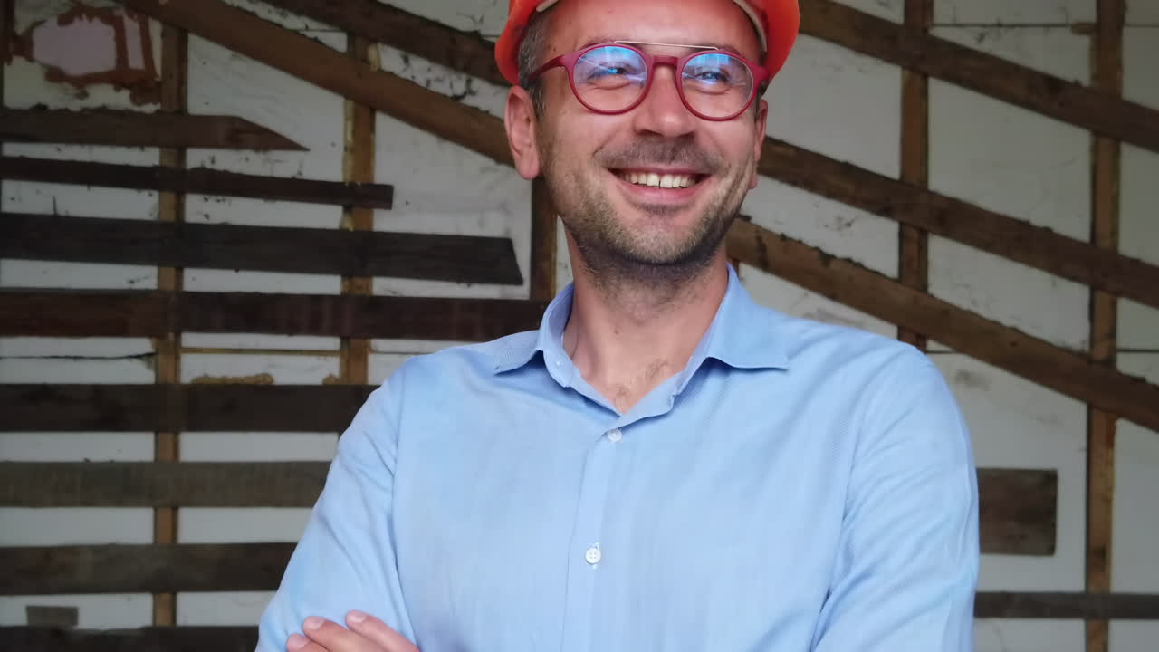 A site manager wearing an orange safety helmet smiling on a construction site