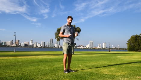 Caucasian-man-with-beard-deliberately-drops-trash-in-green-park,-wide-shot