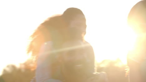 three couples having fun piggybacking at sundown