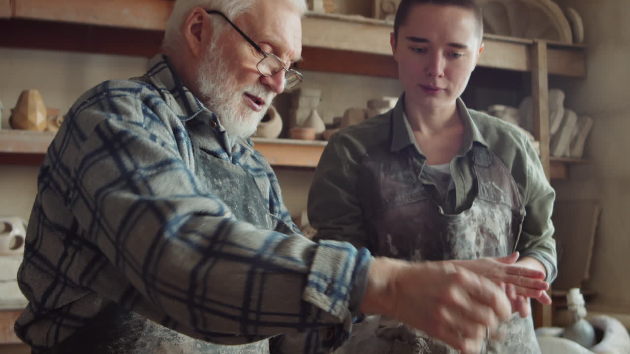Senior Sculptor Explaining How to Work with Clay to Young Woman