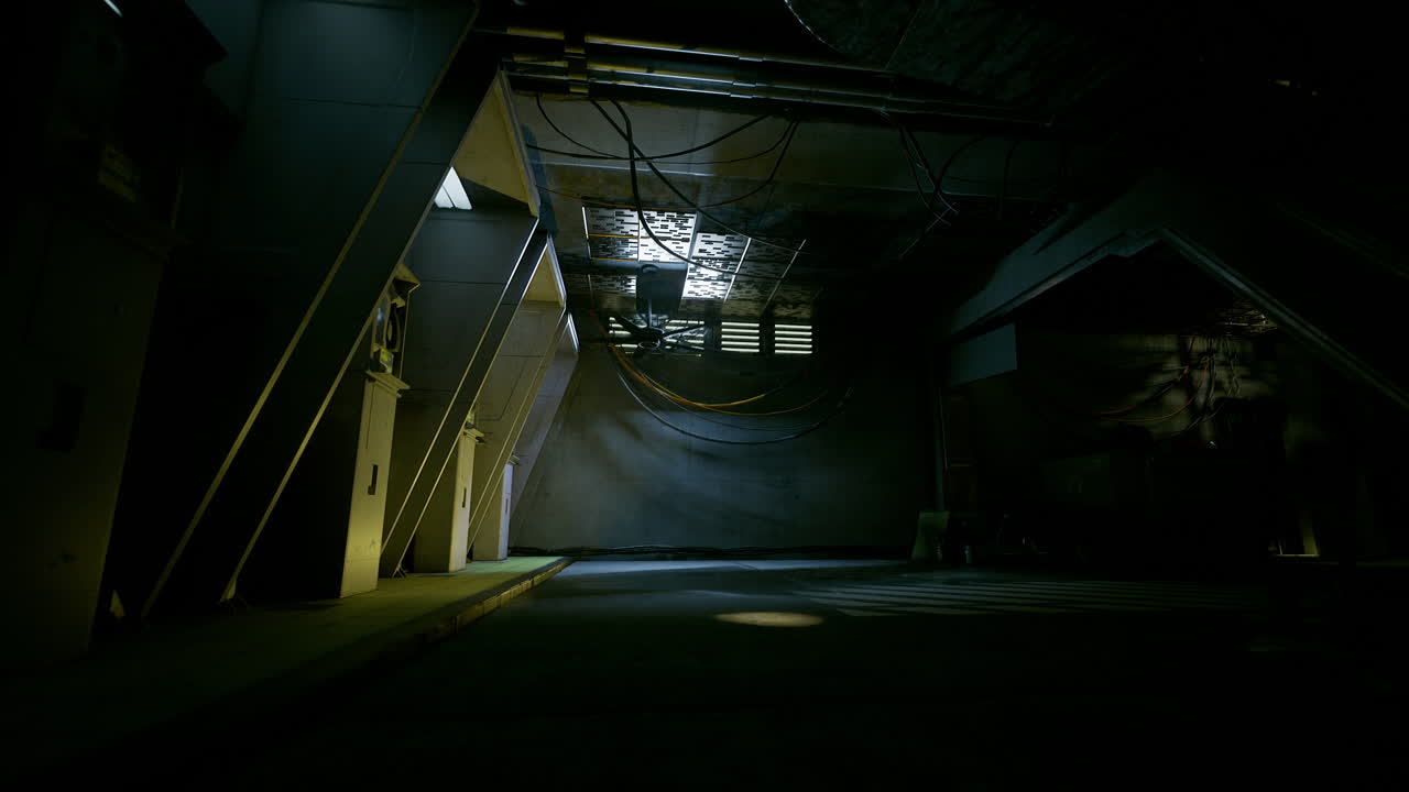 Dimly lit industrial space with shadows and cables in the background