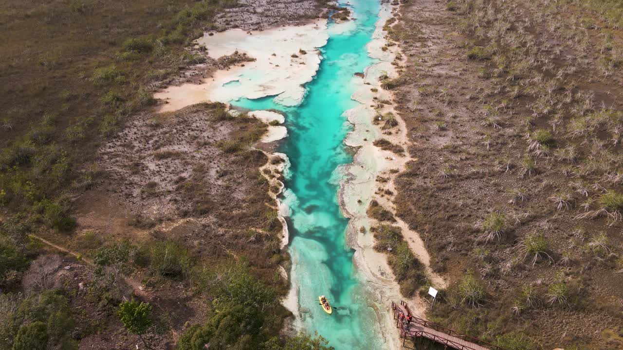 멕시코 바칼라르에 위치한 "로스 라피도스" 급류의 경치를 보여주는 카약 선수들의 위쪽 패닝 드론 샷이 4k로 촬영되었습니다.