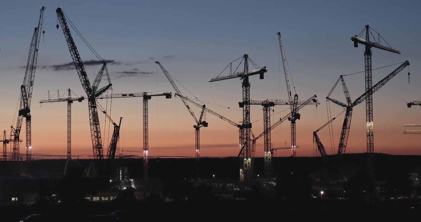 Moody wide angle shot of tower cranes at a semiconductor factory construction zone during the blue hour in Germany