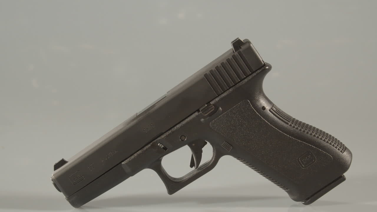 Dolly in to 9mm handgun standing beging ammunition against a white background